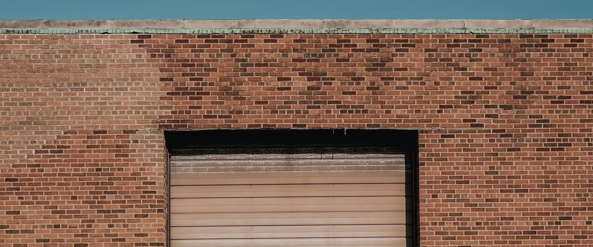 Brick industrial facade with the upper portion of a closed roller door