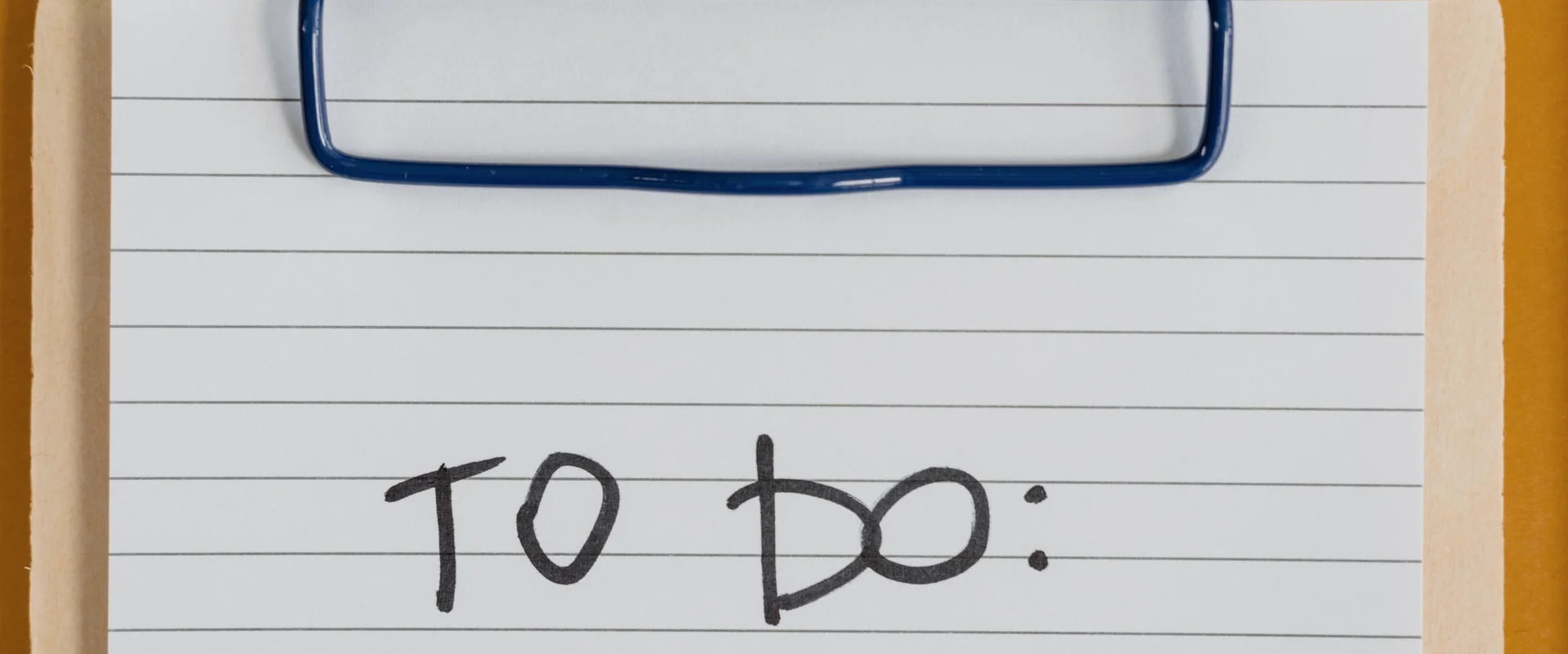 A clipboard with a lined to-do list on an orange desk