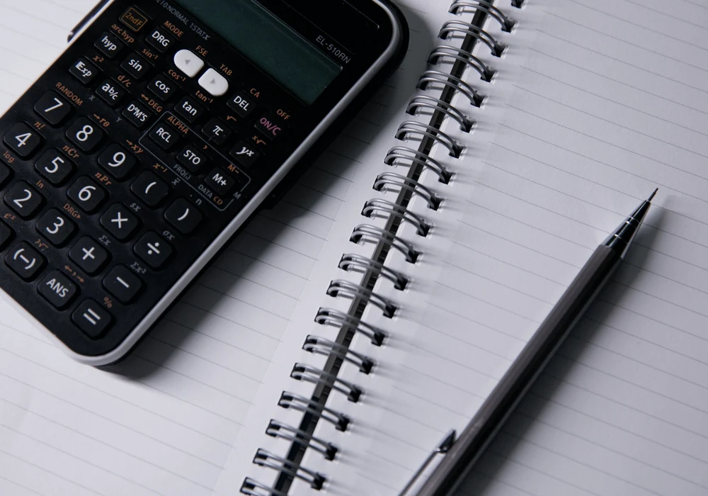 Calculator keypad beside a blank lined notebook and pen