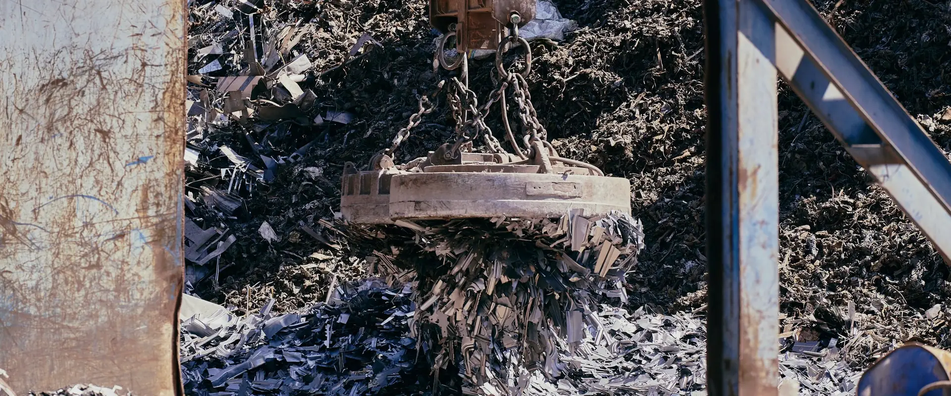 A magnet crane lifting scrap metal in an industrial recycling yard