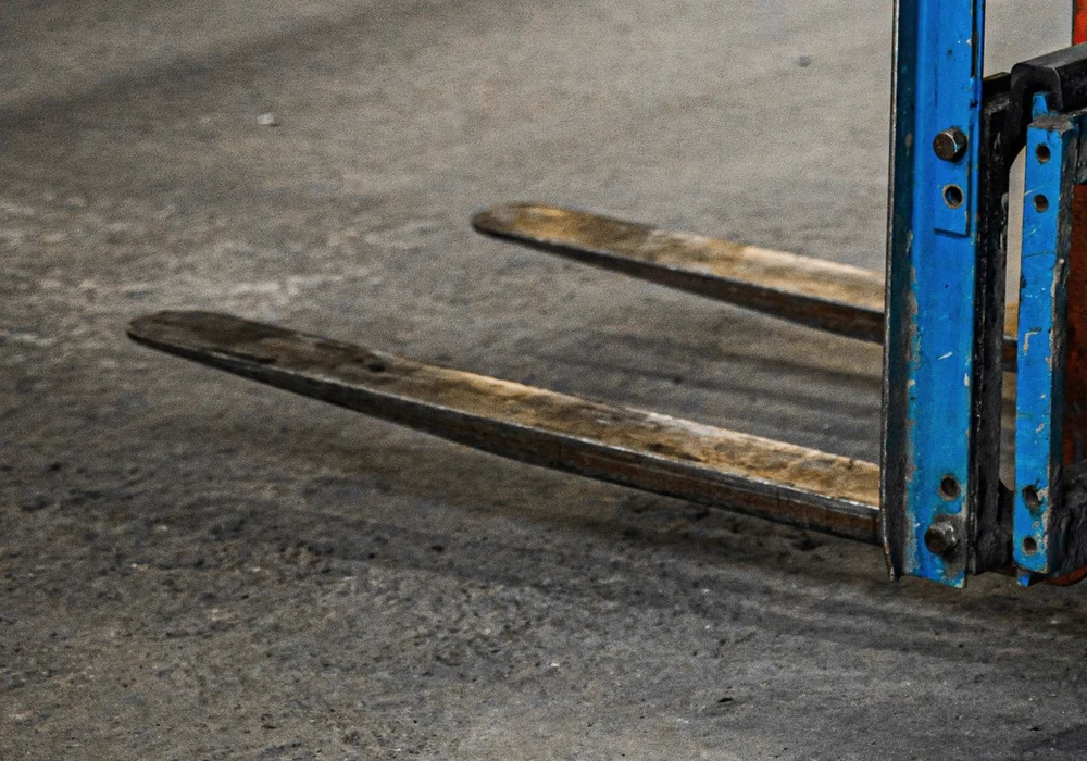 Lowered steel forklift forks on a warehouse floor