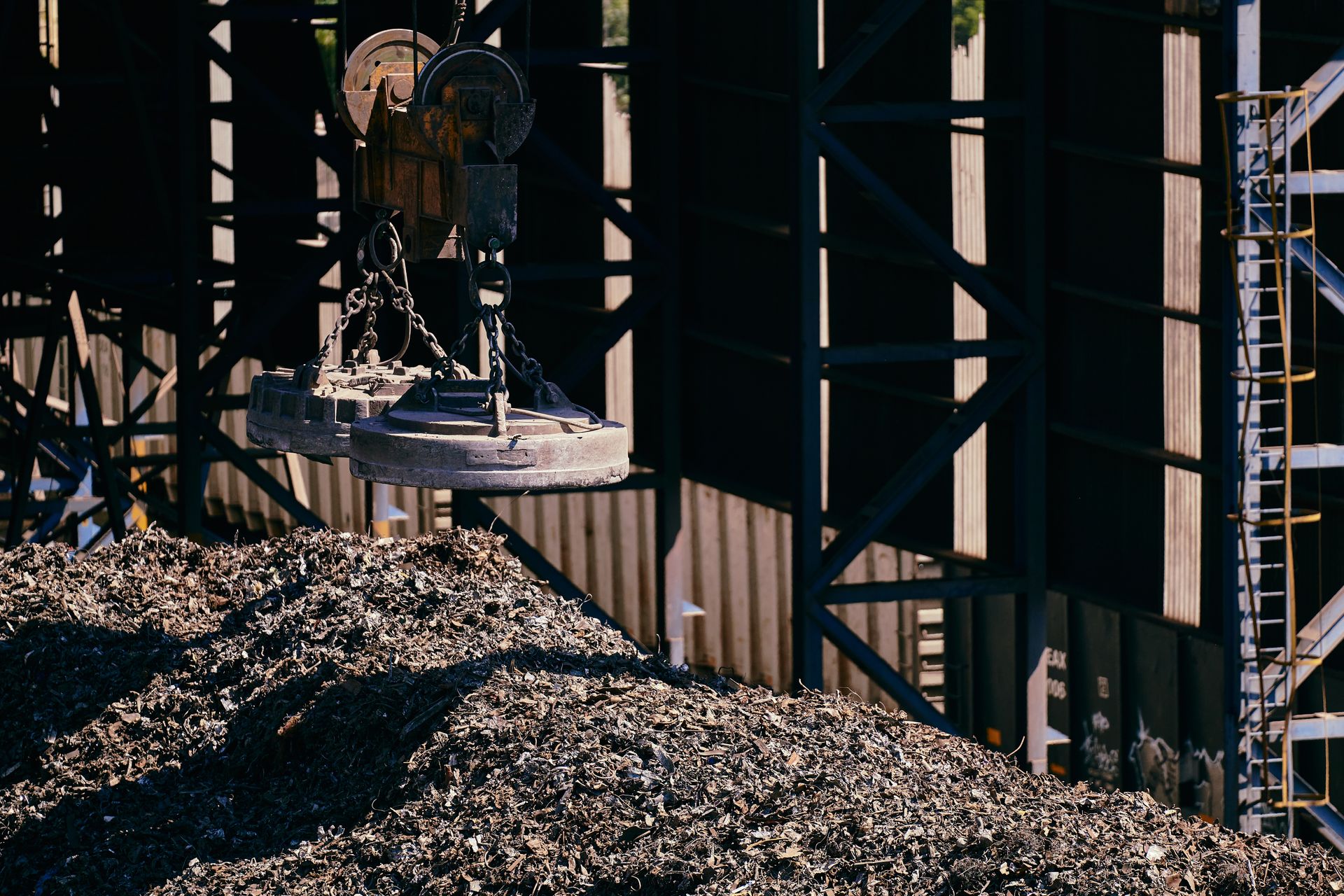 Industrial magnet crane above recycled metal in a processing yard